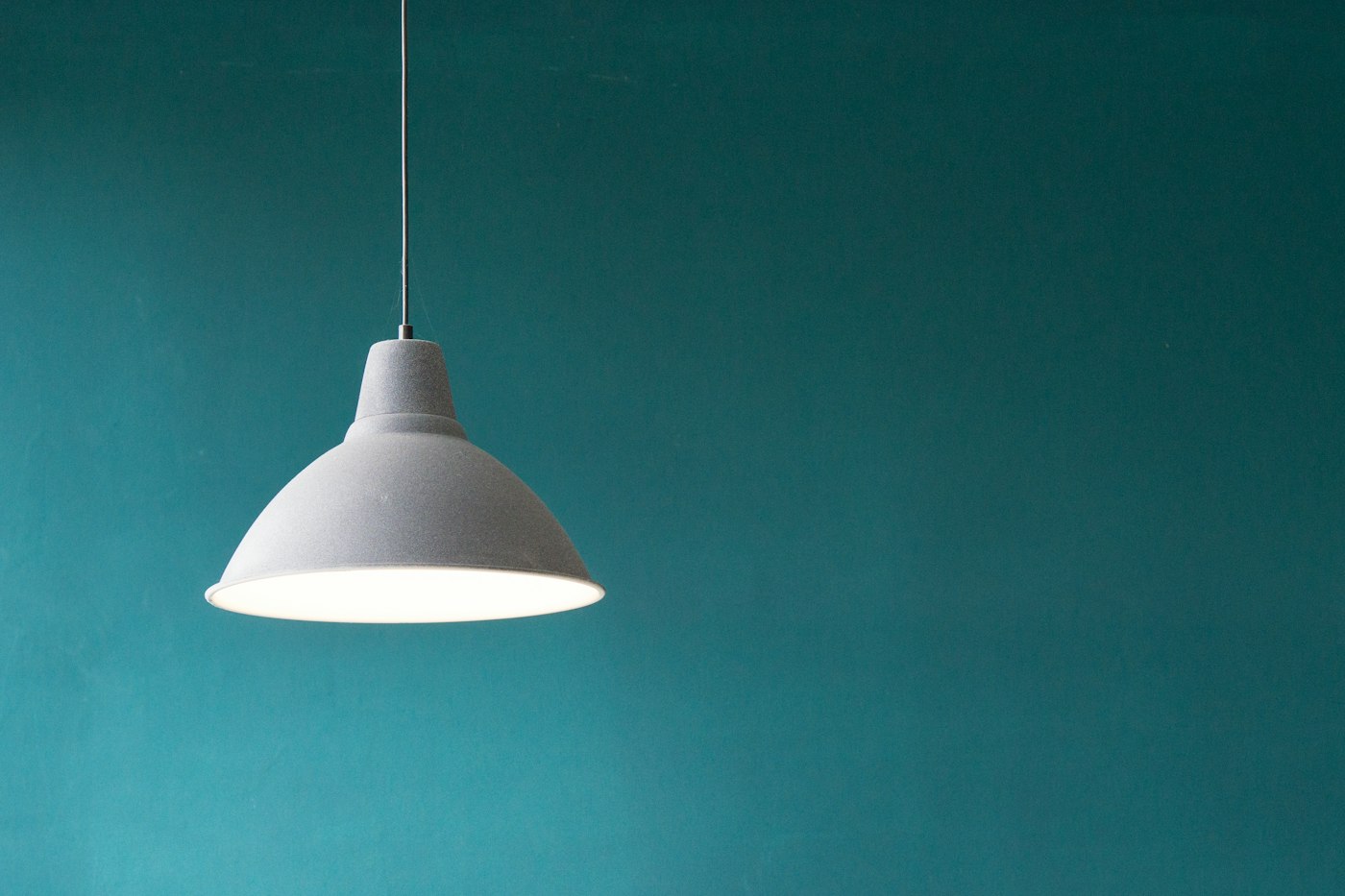 Hanglamp tegen een petrolkleurige muur