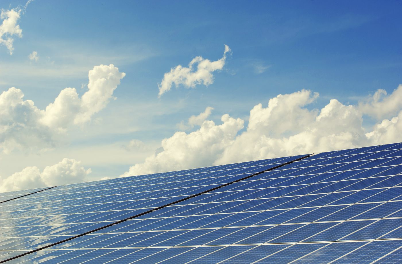 Zonnepanelen onder een blauwe lucht met wolken
