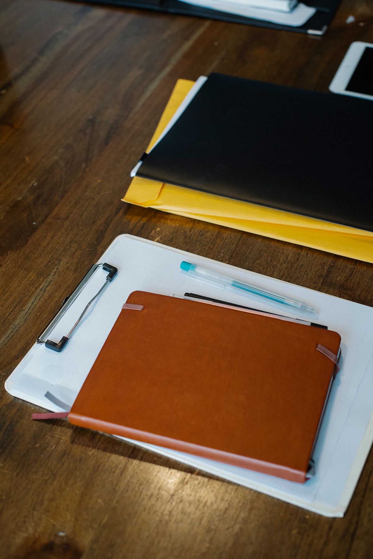 Klembord, notitieboek en enveloppen op een houten bureau