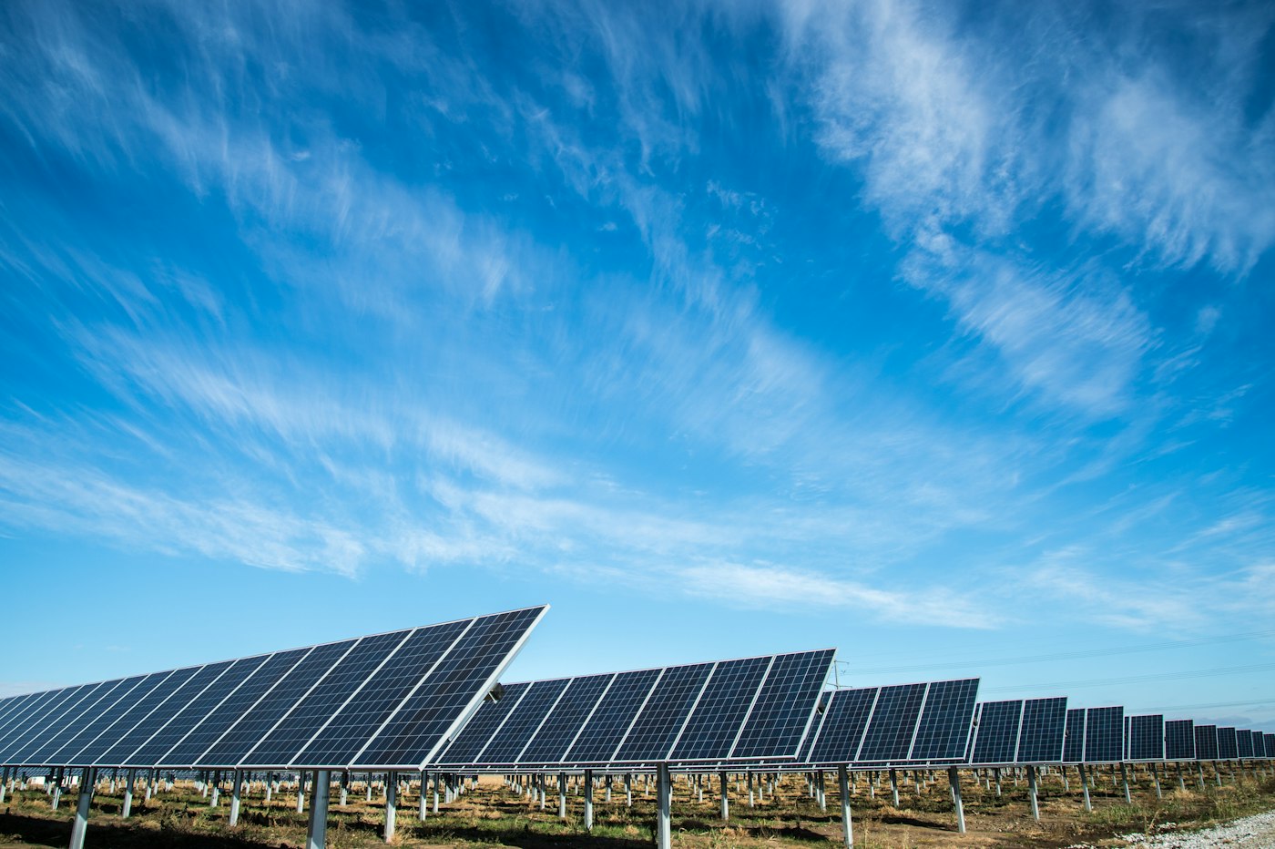 Rijen zonnepanelen onder een blauwe lucht